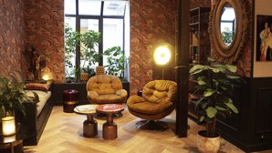 A cozy living room with a sofa, two armchairs, a coffee table, and a bookshelf. - Hôtel Moris (Paris)