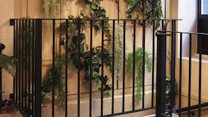 A staircase with a railing, surrounded by various plants and a hanging light fixture. - Hôtel Moris (Paris)