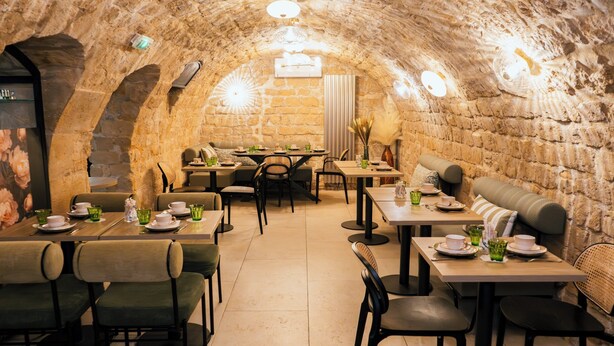 A restaurant with stone walls and tables set for dining. - Hôtel Moris (Paris)