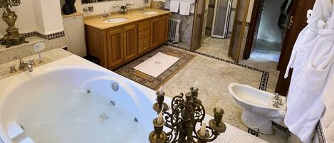 A spacious bathroom with a large bathtub, a double sink vanity, and a separate toilet area.