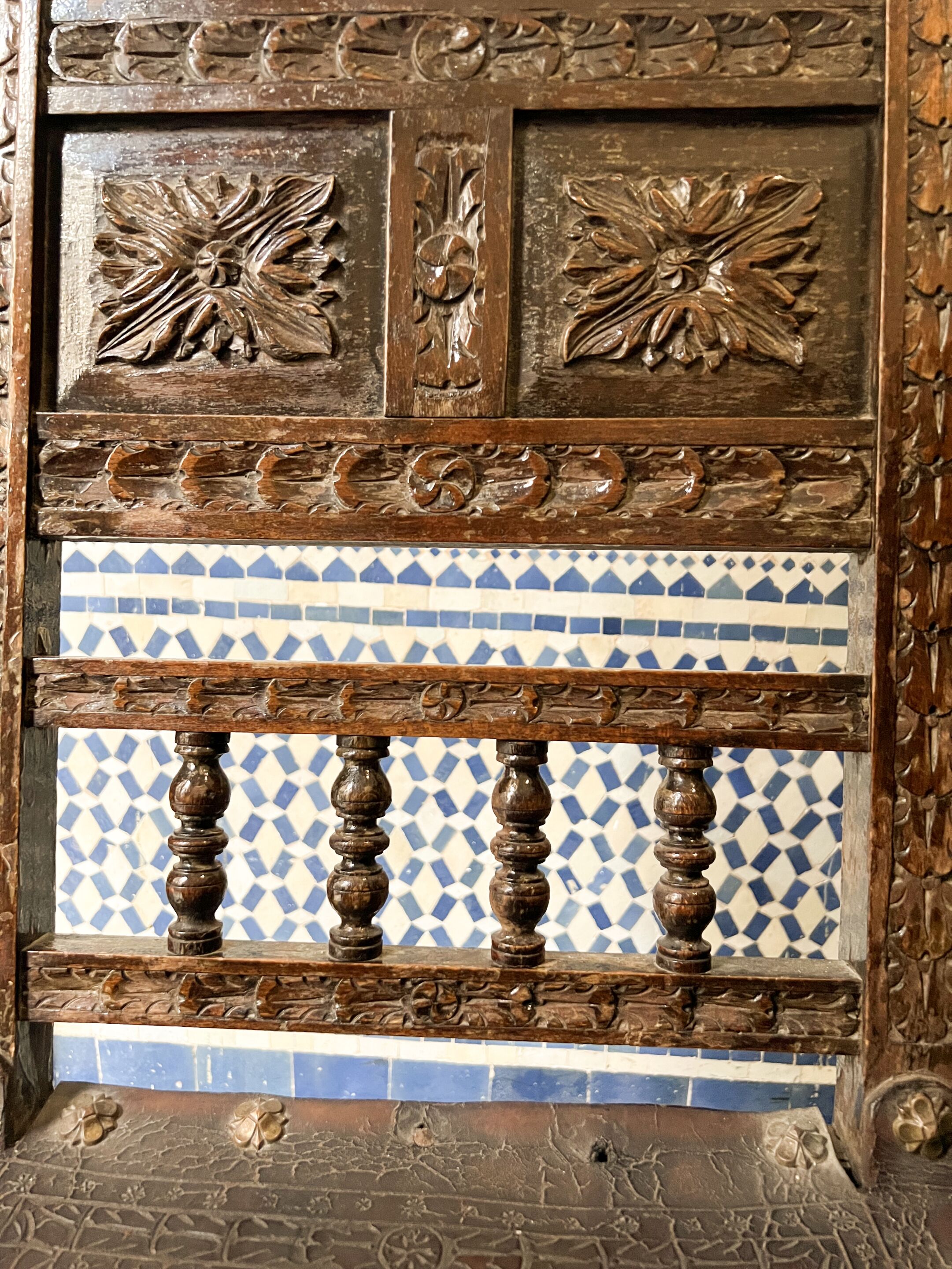 Un panel de madera con tallas detalladas y una sección de azulejos abajo.