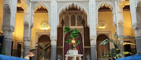 A luxurious interior with ornate arches, a central seating area with blue sofas, and a patterned floor.