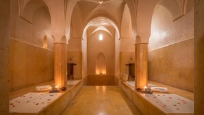 Un pasillo con techos abovedados y una fuente de luz central. A ambos lados, bancos con toallas y velas.