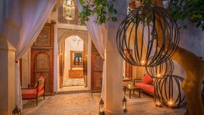 Un interior con diseño tradicional, que presenta un arco central, un área de descanso con cojines y faroles decorativos.