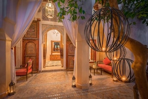 Un interior con diseño tradicional, que presenta un arco central, un área de descanso con cojines y faroles decorativos.