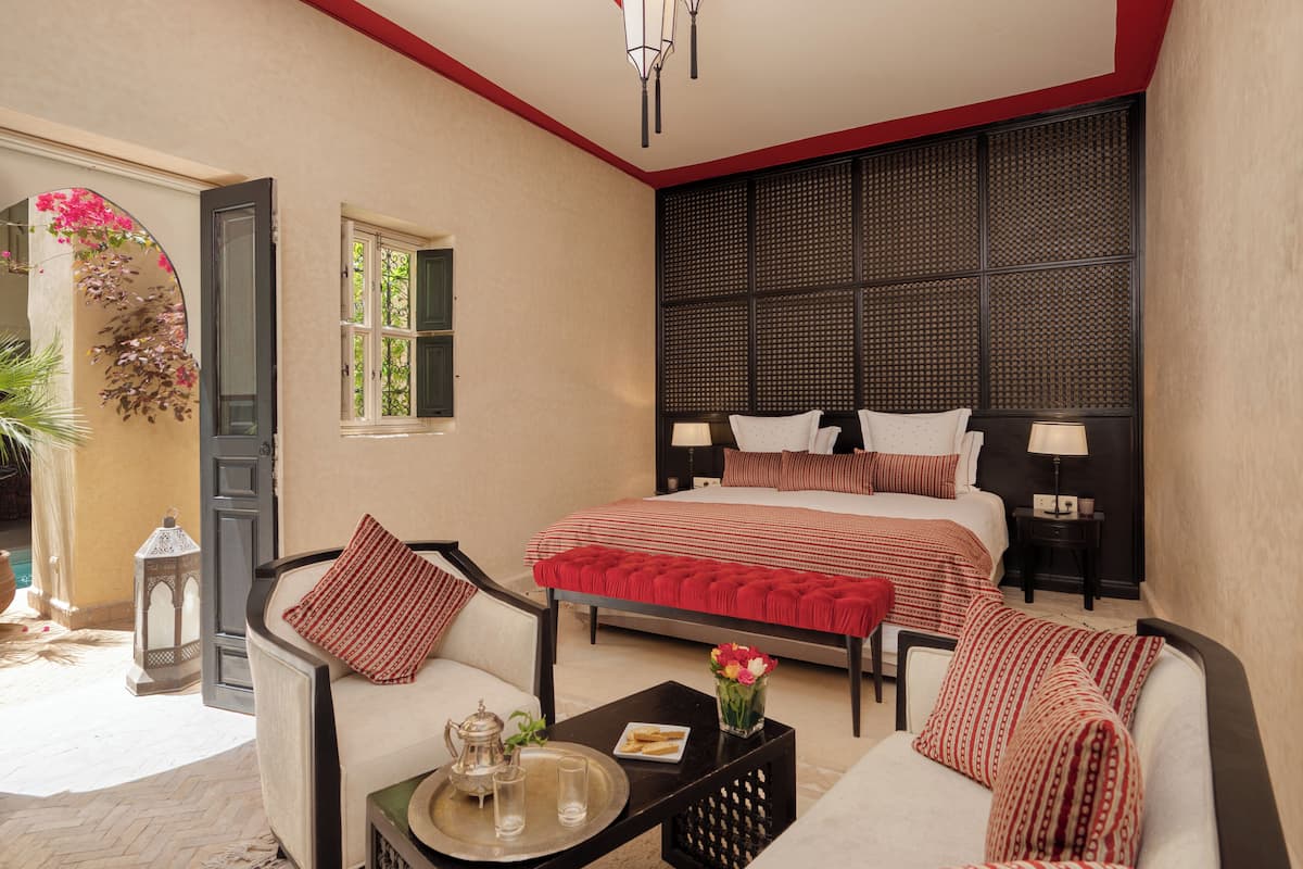 A bedroom with a large bed, two bedside tables, a sofa, and a small table with a tray.