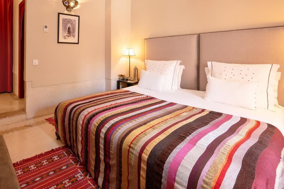 A hotel room with a large bed, a bedside lamp, a framed picture on the wall, and a red curtain.