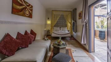 A hotel room with a bed, a sofa, a small table with fruit, and a view of the outside.