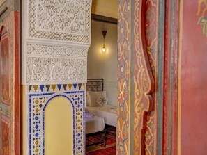 Une pièce comprenant un lit, un luminaire suspendu et un mur décoratif orné de motifs complexes.