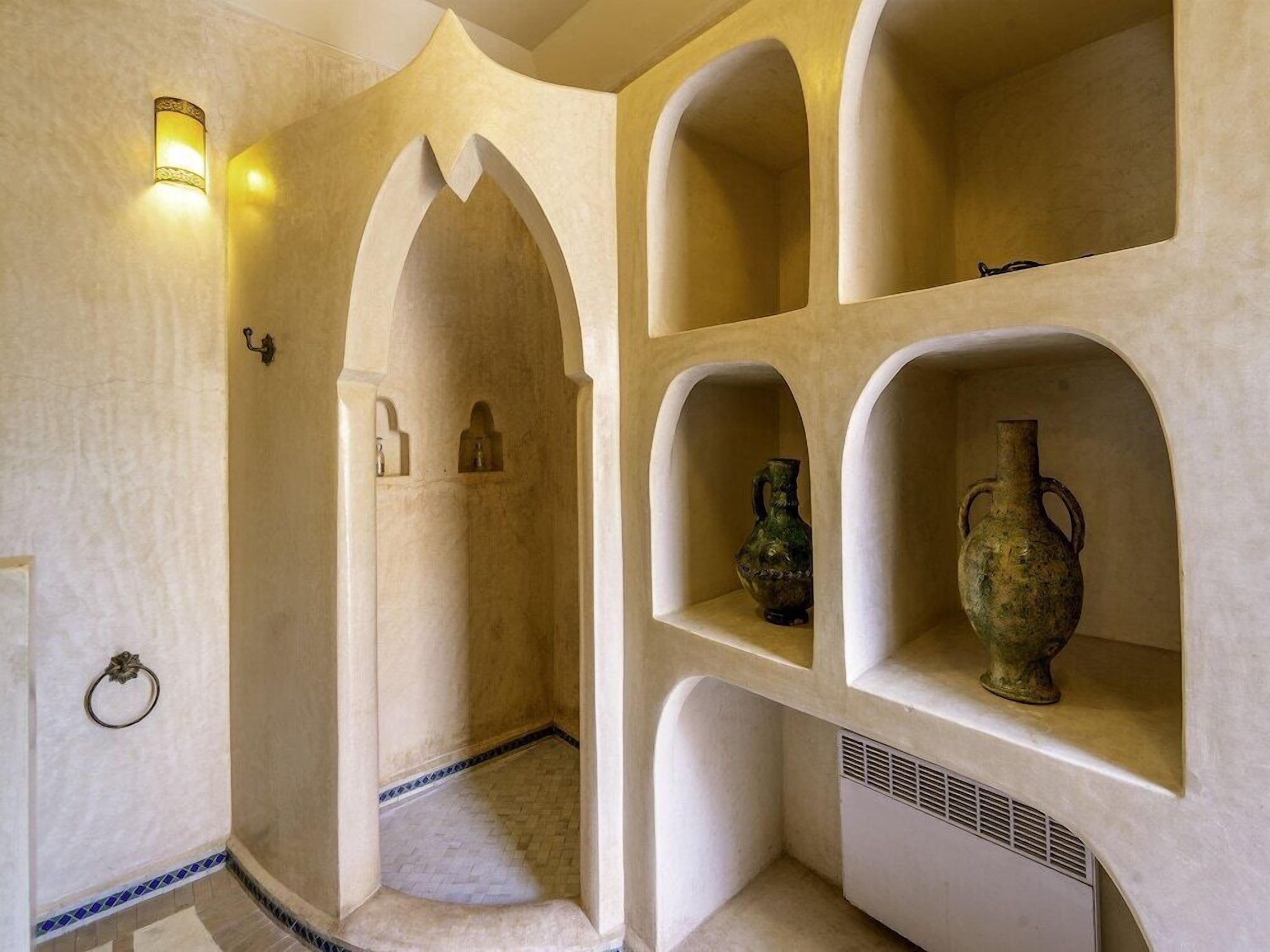 Ein Zimmer mit einer gewölbten Wand, einer integrierten Ablage mit Vasen und einer wandmontierten Leuchte.