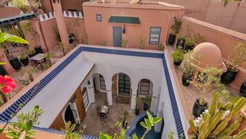 A courtyard with a pool, potted plants, and a traditional architectural style.