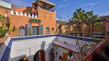 A courtyard with a building featuring arches and a balcony.