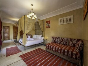 A bedroom with a four-poster bed, a sofa, a chandelier, and artwork on the walls. - Palais Tinmel Marrakech (Marrakech)