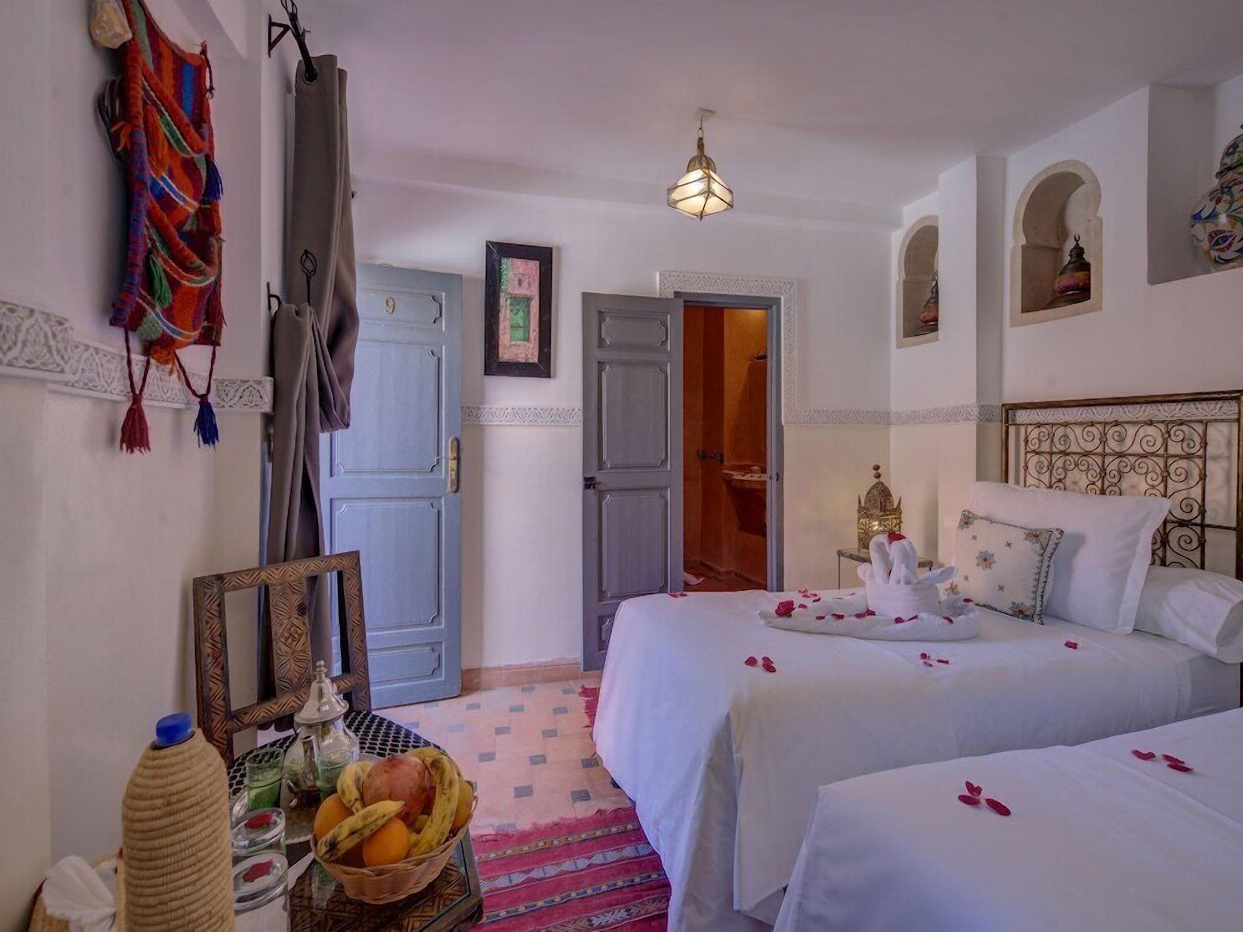 Ein Hotelzimmer mit zwei Betten, einem Spiegel, einer Wandleuchte und einer Tür zu einem Badezimmer.