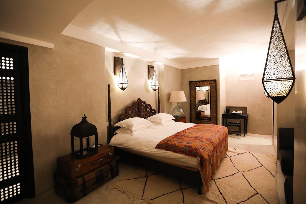 A bedroom with a bed, a nightstand, a lamp, a mirror, and a decorative lantern.