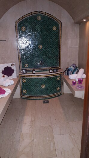 A bathroom with a green mosaic wall, a sink, and towels. - Helnan Chellah Hotel (Rabat)