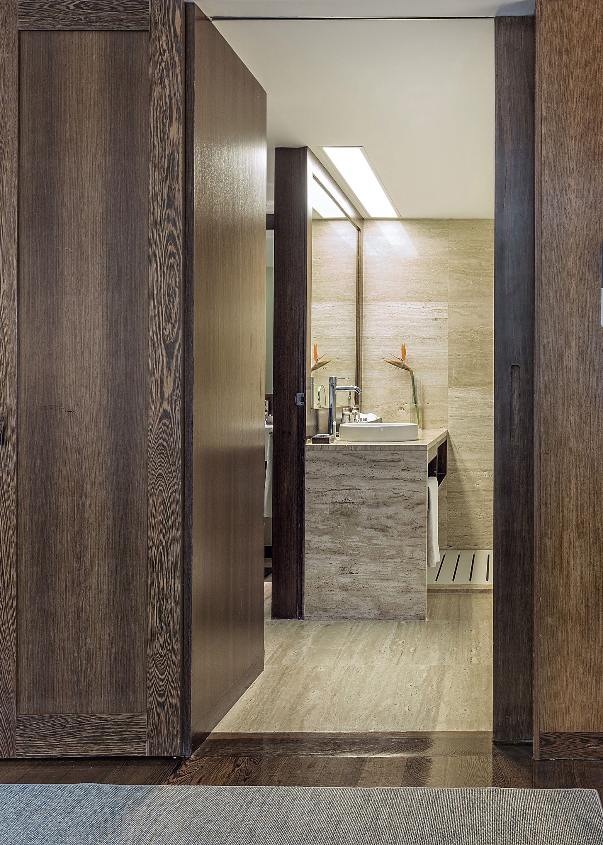Un baño moderno con tocador de madera, un lavamanos y un espejo.
