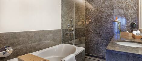 A modern bathroom with a freestanding bathtub, a glass-enclosed shower, and a marble-tiled vanity.
