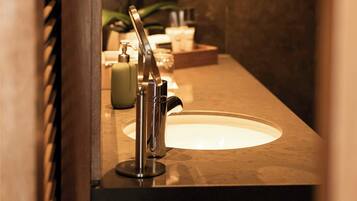 Un baño con lavamanos, espejo y artículos de tocador.