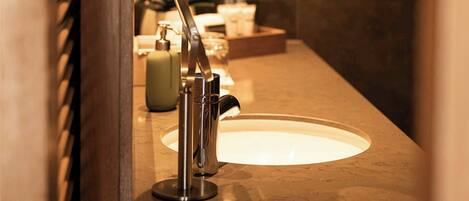 A bathroom with a sink, mirror, and toiletries.