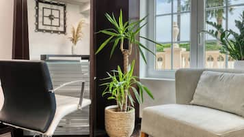 Ein modernes Zimmer mit einem schwarzen Ledersessel, einem beige farbenen Sofa, einem großen gewebten Blumentopf und einer Wanduhr.