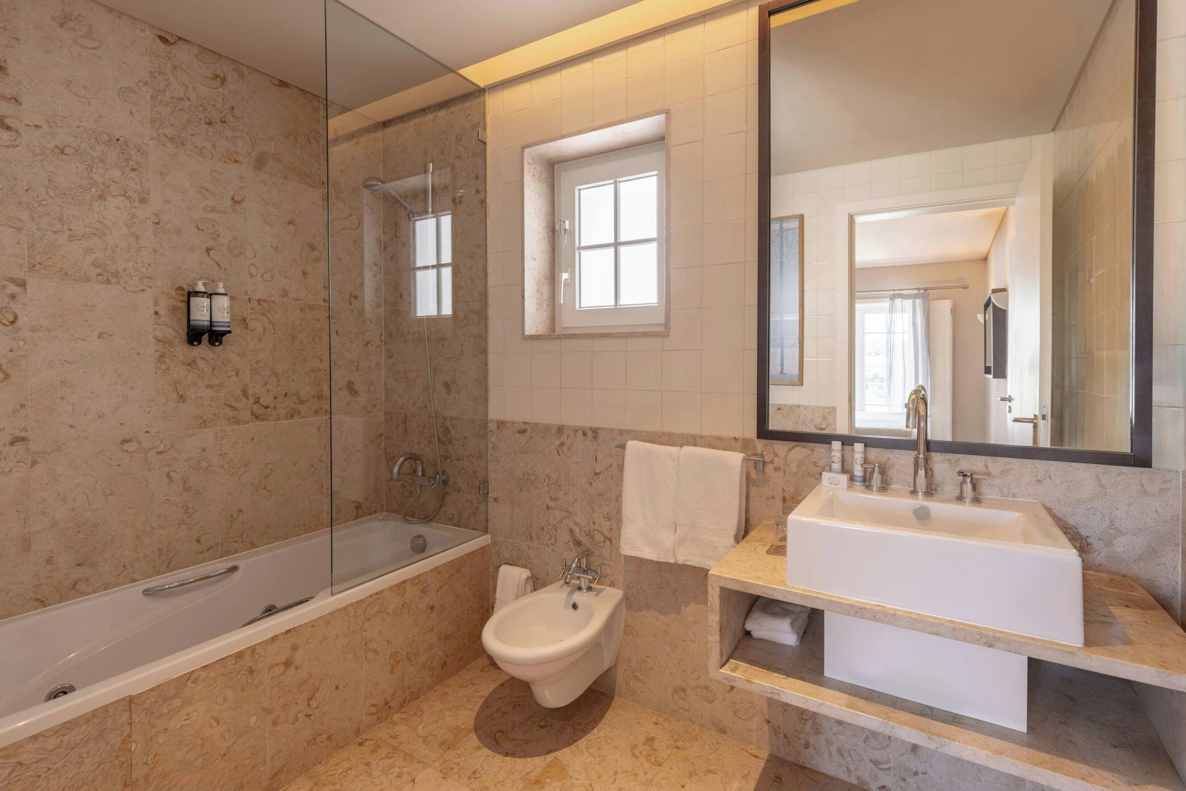 Een moderne badkamer met een badkuip, toiletbrons, wastafel en een grote spiegel.