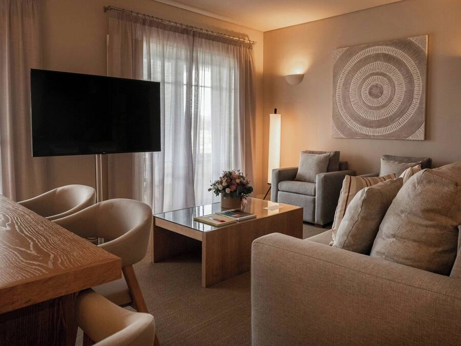 Ett modernt vardagsrum med en platt-TV, en soffa, ett soffbord med en vas med blommor och ett konstverk som hänger på väggen.