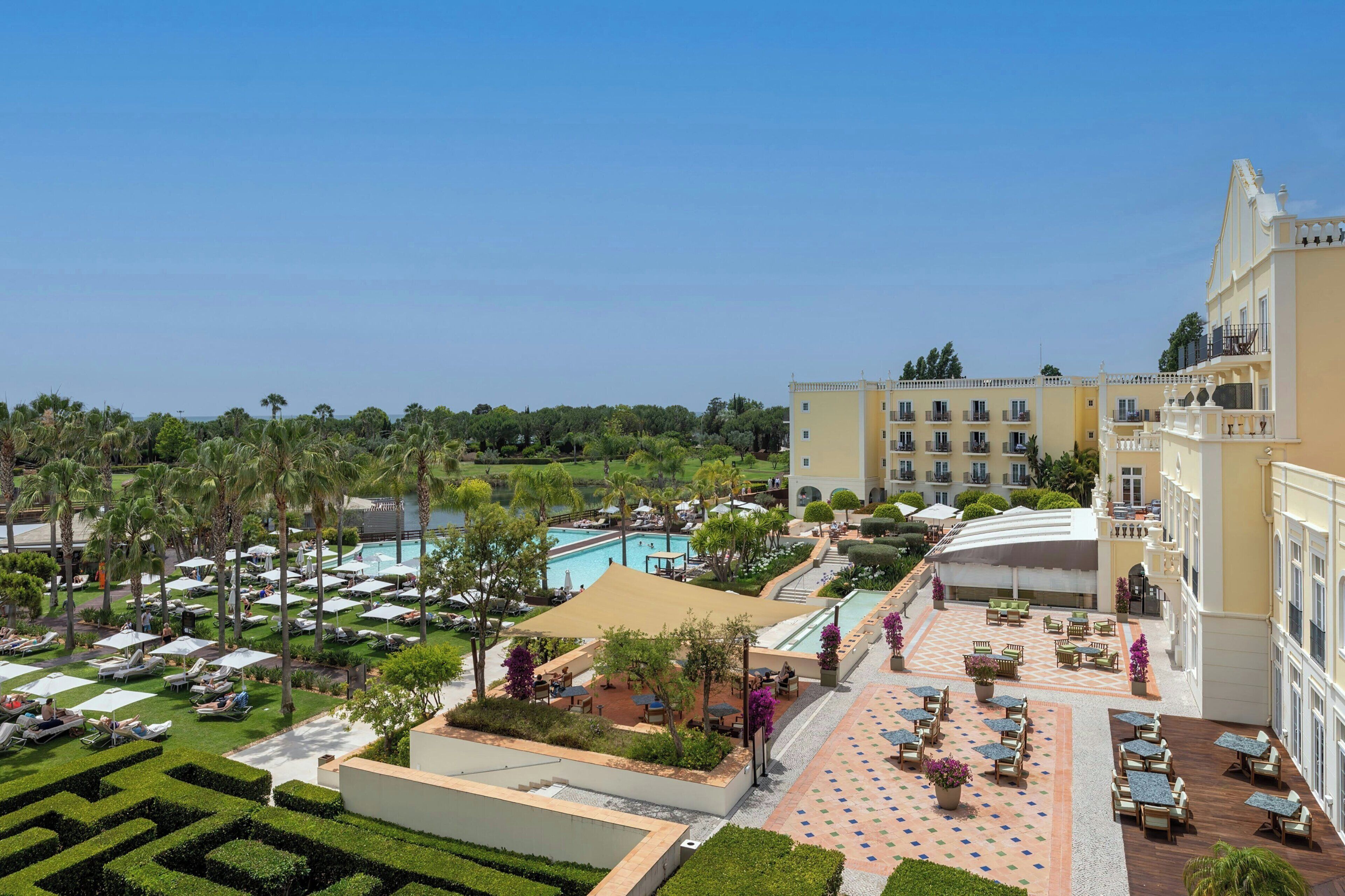 A resort with a pool, outdoor seating, and manicured gardens.