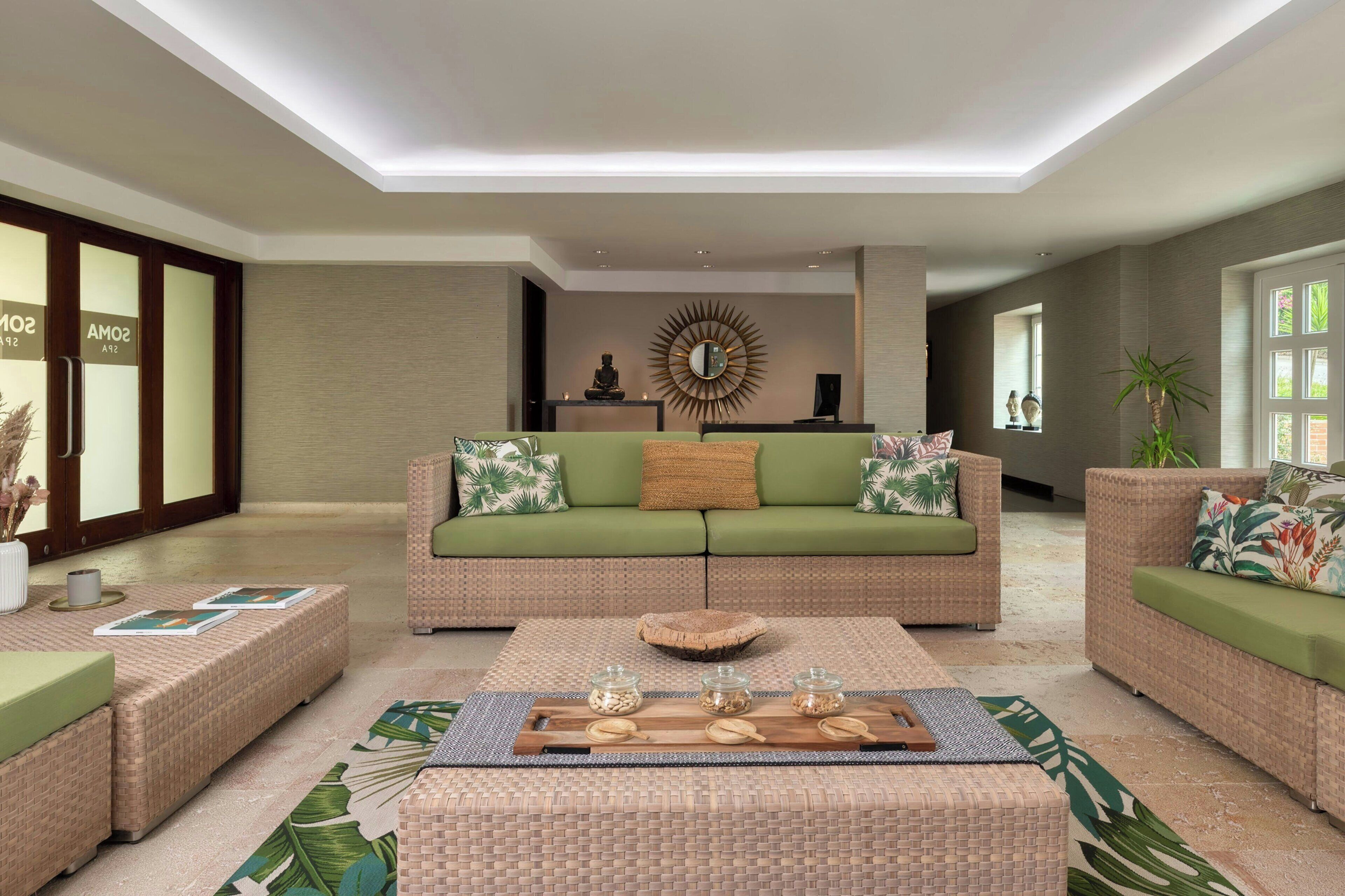 A modern living room with a green sofa, wicker furniture, and a decorative mirror.