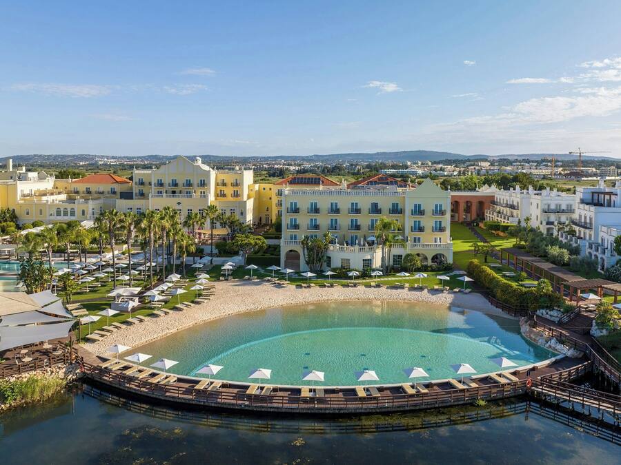 Ein Resort mit großem Pool, mehreren Gebäuden und Strandabschnitt.