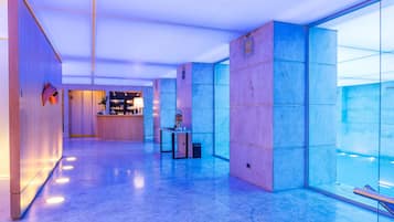 Un hall d’entrée moderne avec un comptoir d’accueil, un espace salon et un mur en verre.