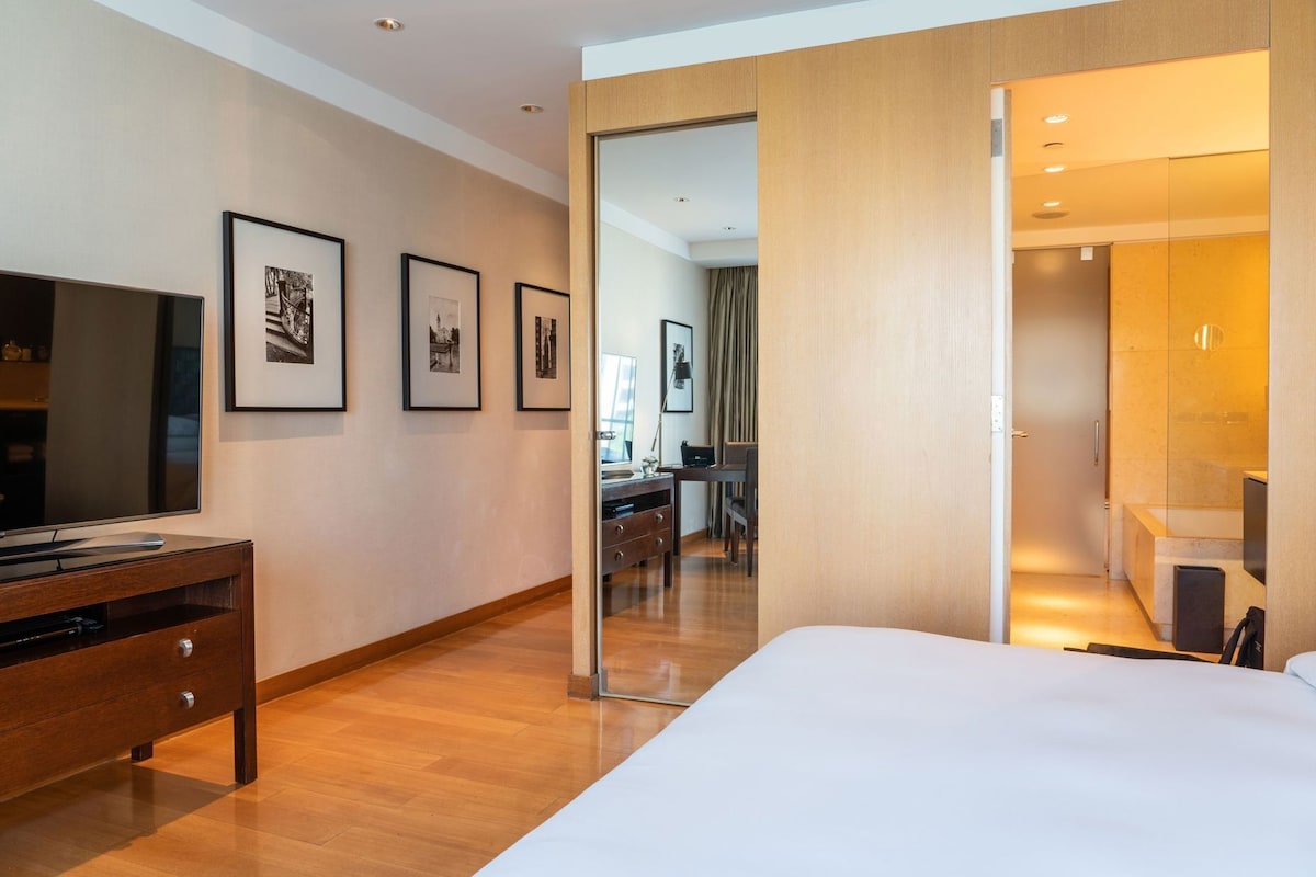 Une chambre d’hôtel avec un lit, une télévision, un bureau et des tableaux accrochés au mur.