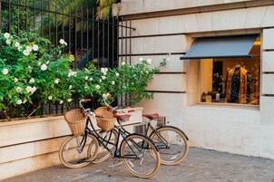 Dos bicicletas estacionadas frente a un edificio con un escaparate que muestra un maniquí.