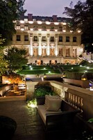 Un hotel elegante con una fachada luminosa, césped cuidado y zonas de estar al aire libre.