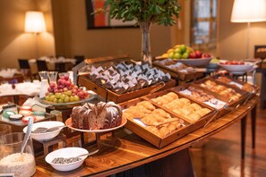 A buffet with various food items including fruits, pastries, and a cake.
