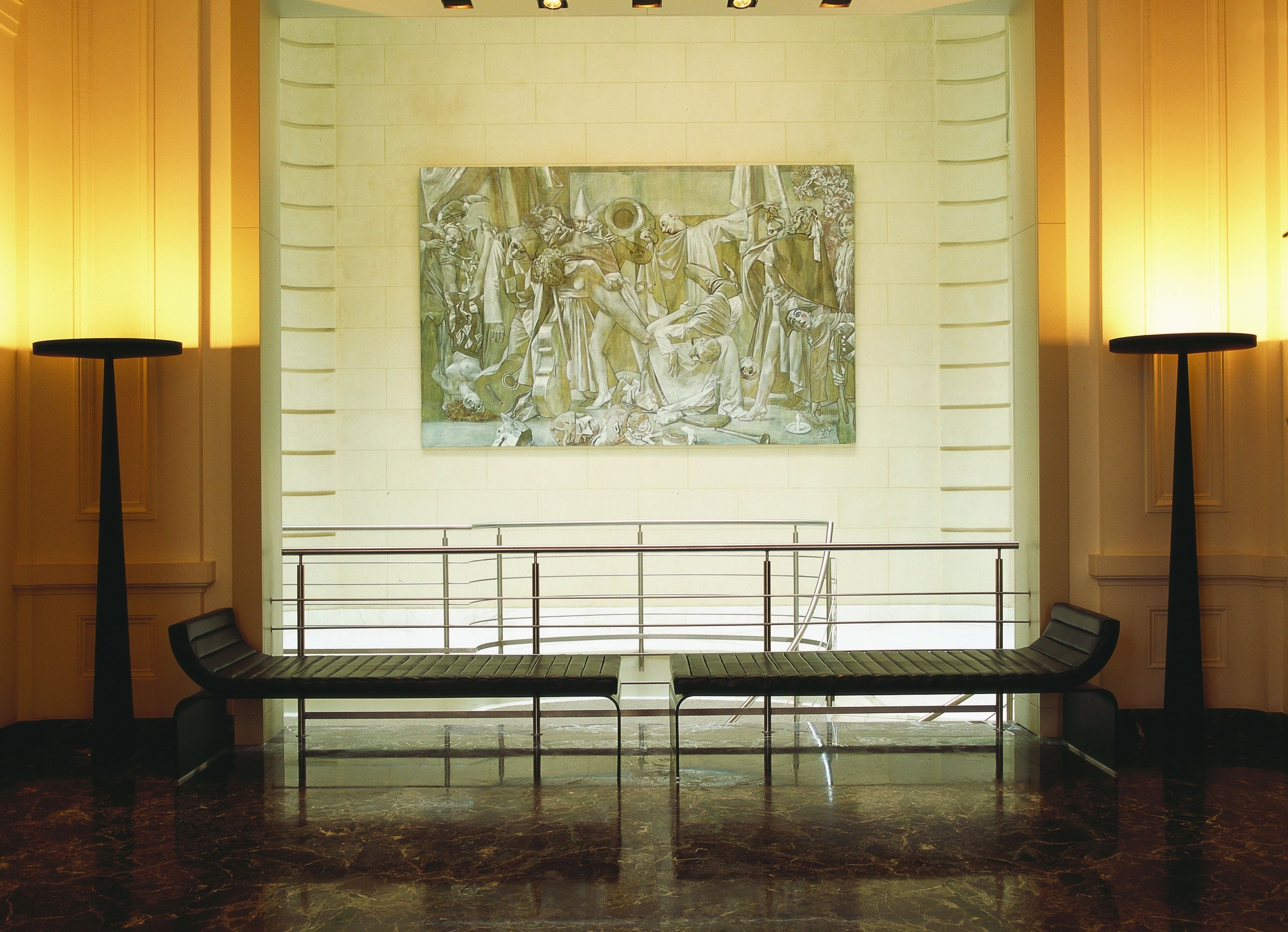 A lobby with a marble floor, a bench, and a large classical painting on the wall.