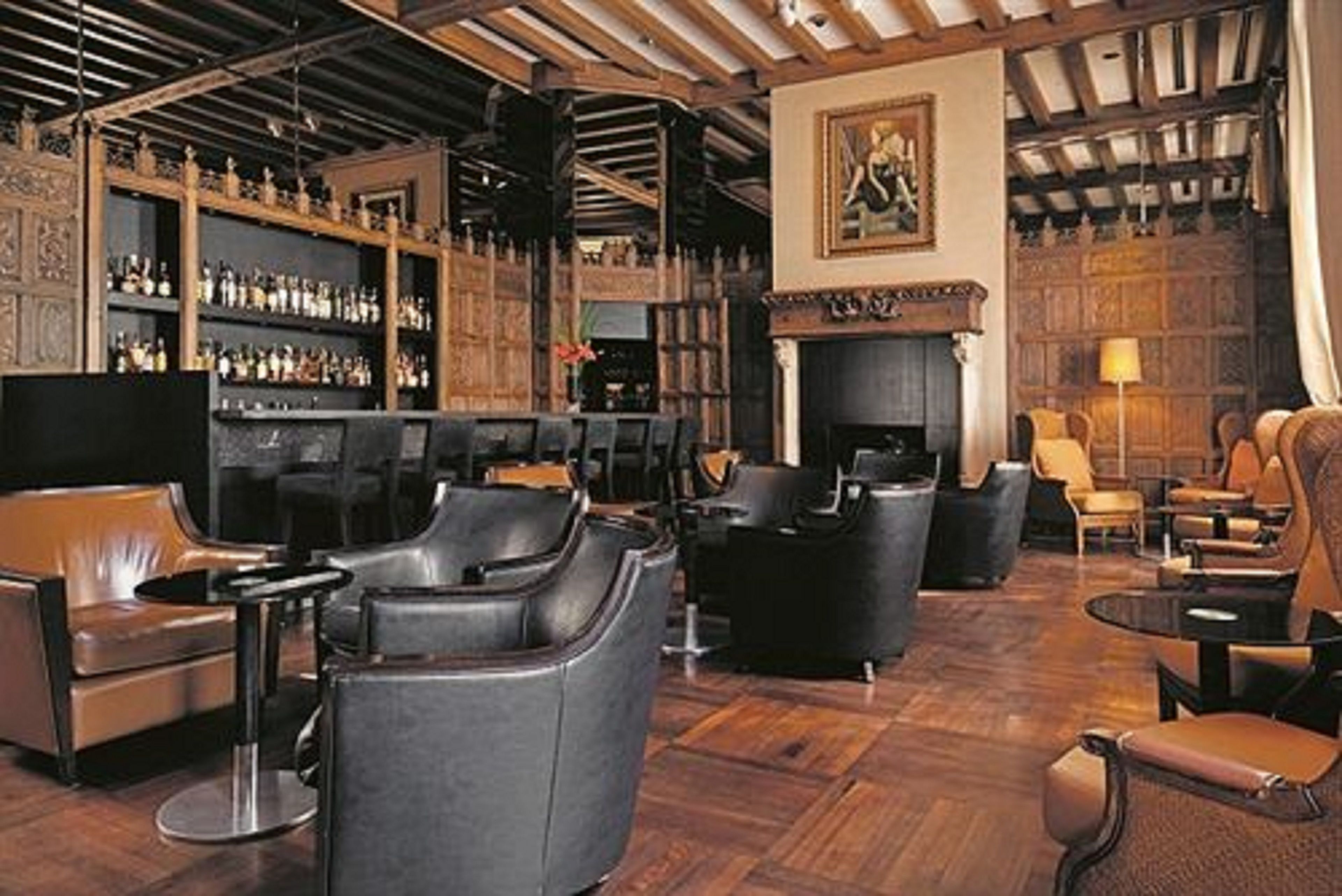 A bar area with leather seating, a fireplace, and shelves of bottles.