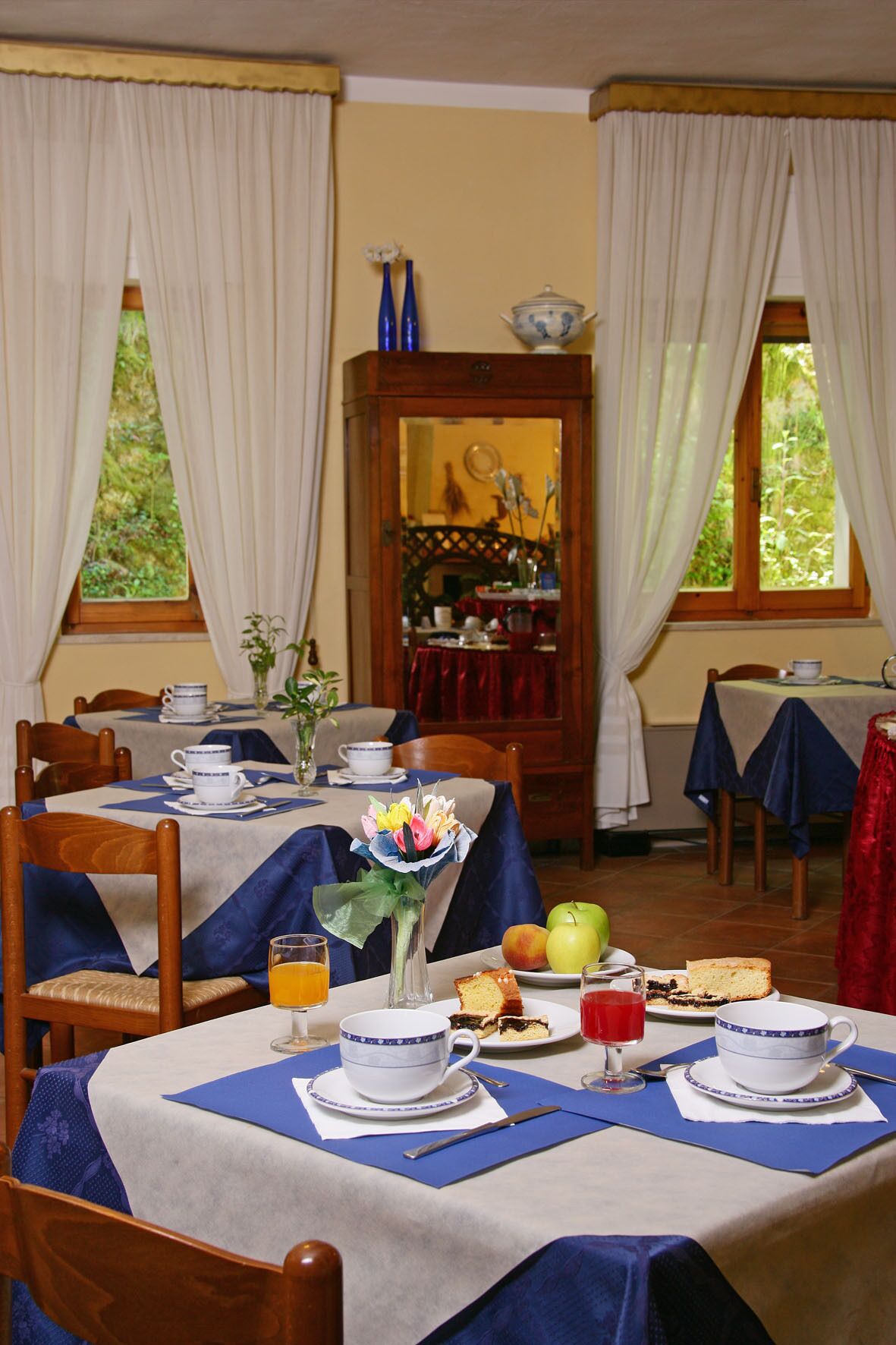 Ein Esszimmer mit gedeckten Tischen für das Frühstück, mit Früchten, Gebäck und Getränken.