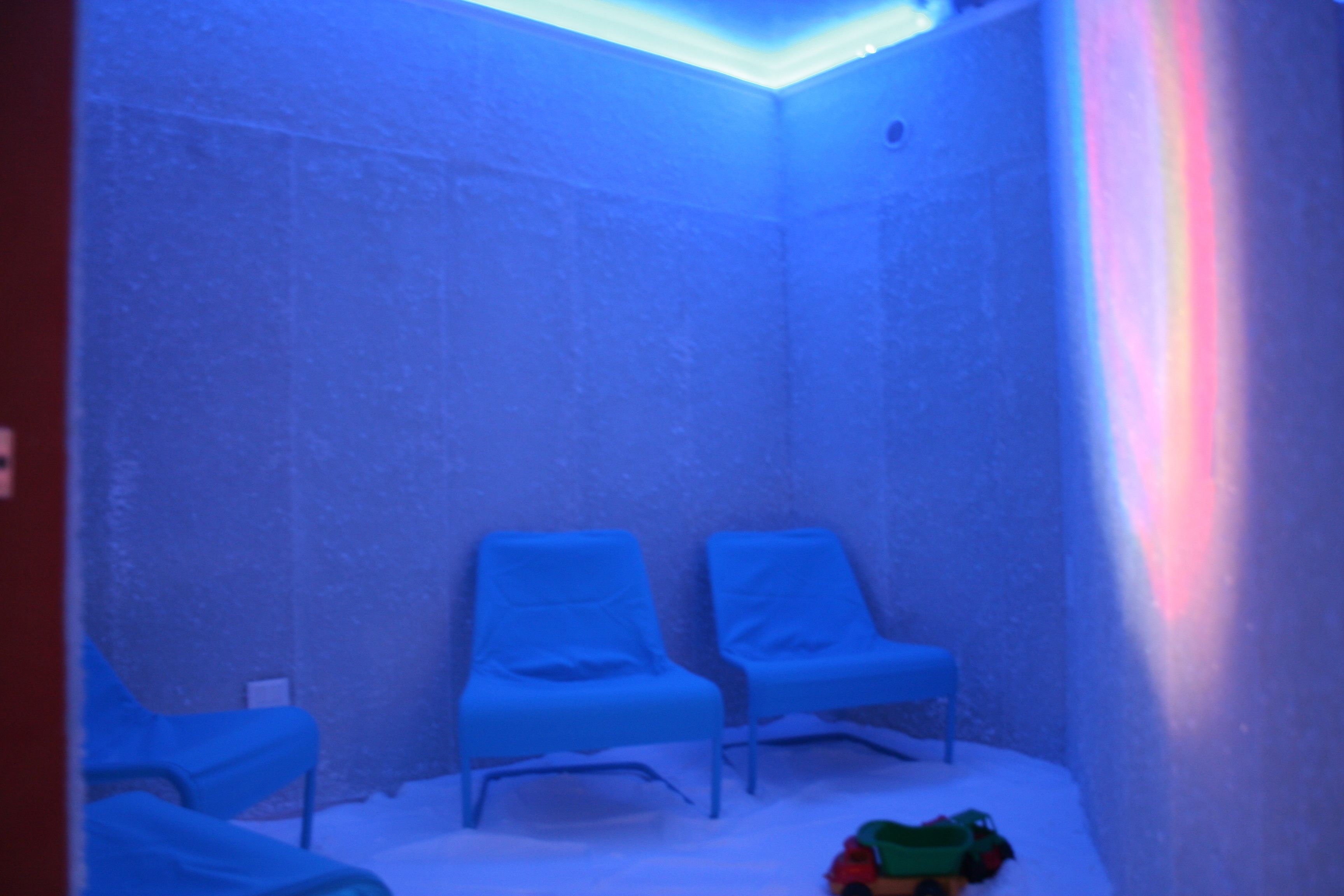 A room with two blue chairs, a small table, and a toy on the floor.