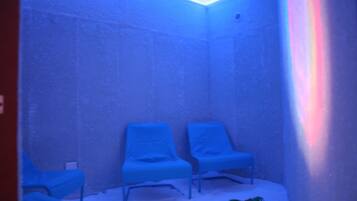 A room with two blue chairs, a small table, and a toy on the floor.