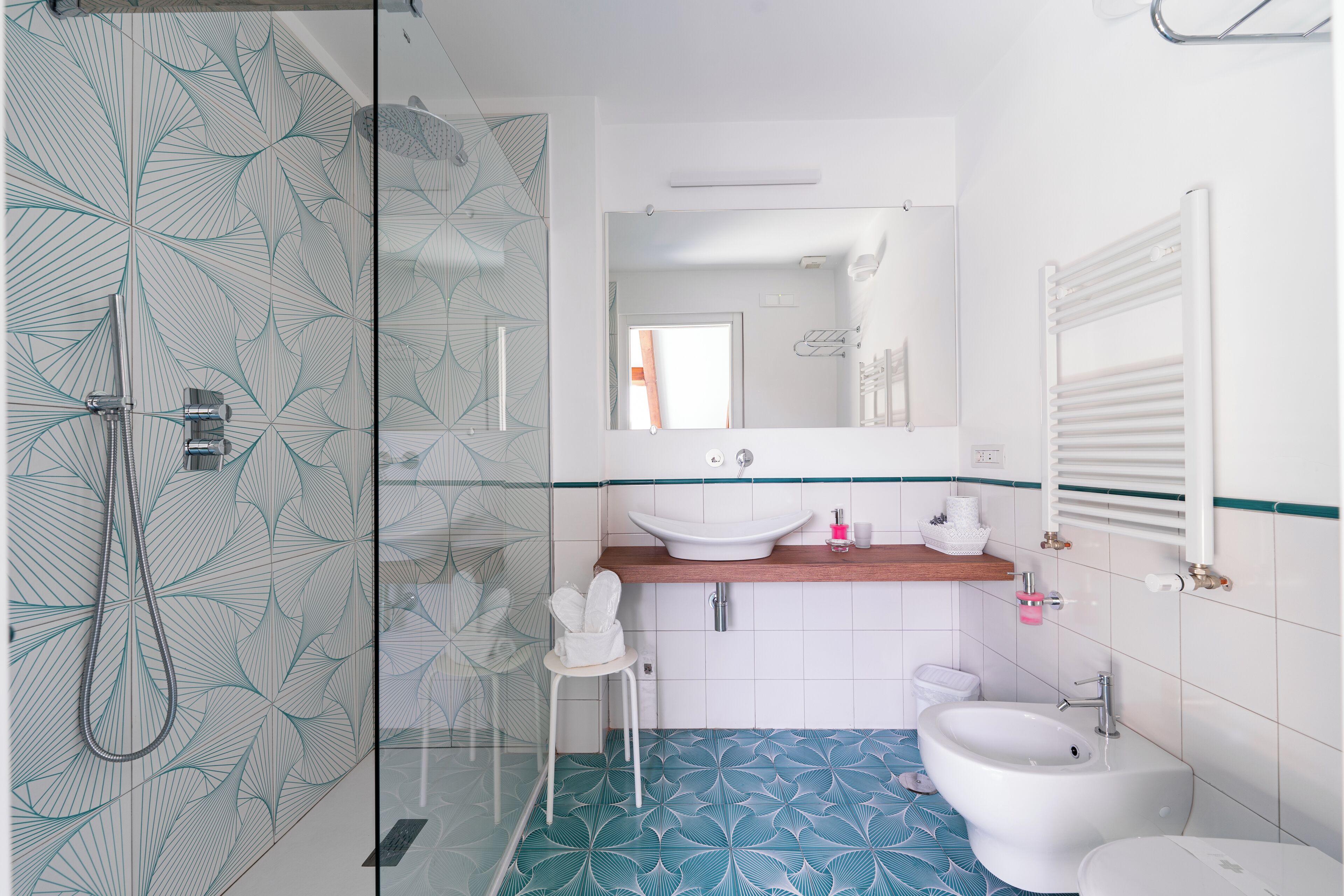A bathroom with a glass shower enclosure, a sink, a bidet, and a toilet.
