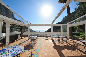 Une terrasse extérieure avec des tables et des chaises, un sol à motifs et une vue sur la mer.