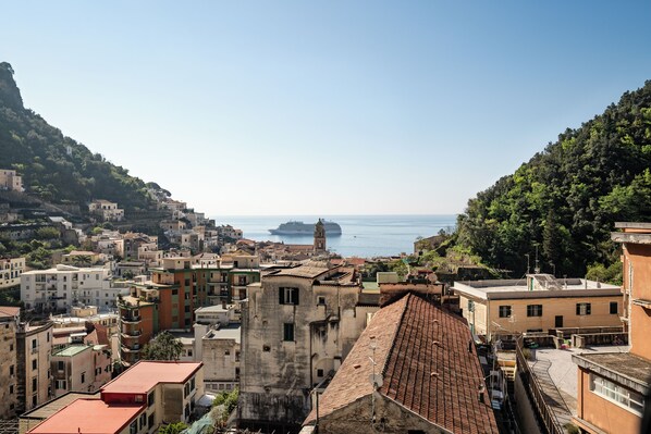 Un paisaje urbano costero con edificios, una iglesia destacada y un crucero en la distancia.