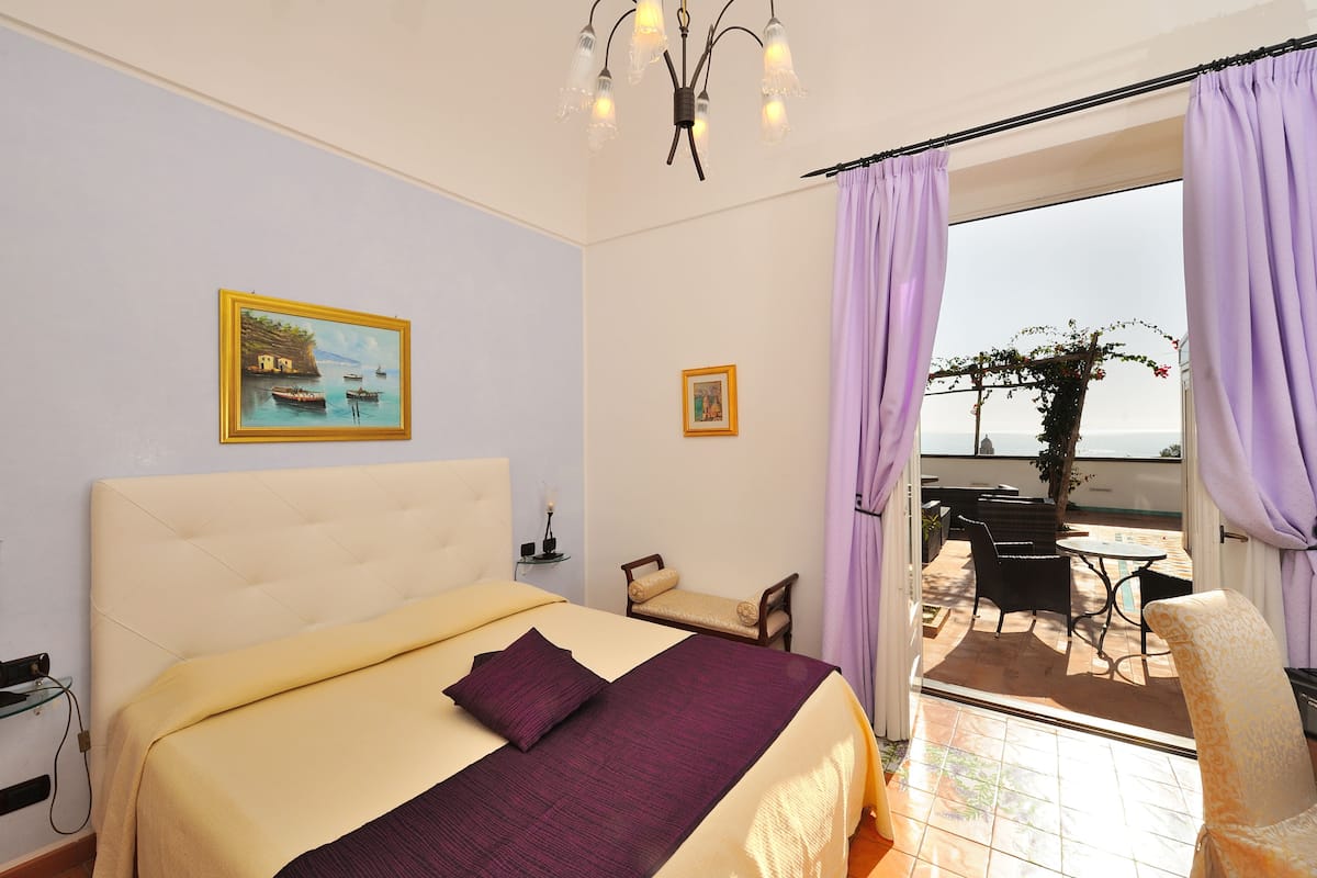 Ein Hotelzimmer mit Bett, Sessel, Tisch und Meerblick.