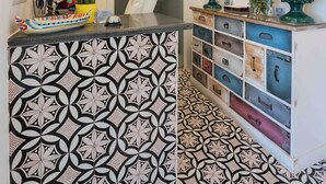 Une cuisine avec des carreaux décoratifs, une lampe d’ornement et un tableau au mur.