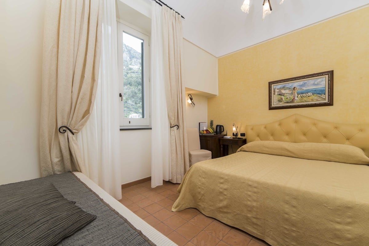 Ein Schlafzimmer mit einem Bett, einem Schreibtisch, einem Stuhl und einem Fenster mit Vorhängen.