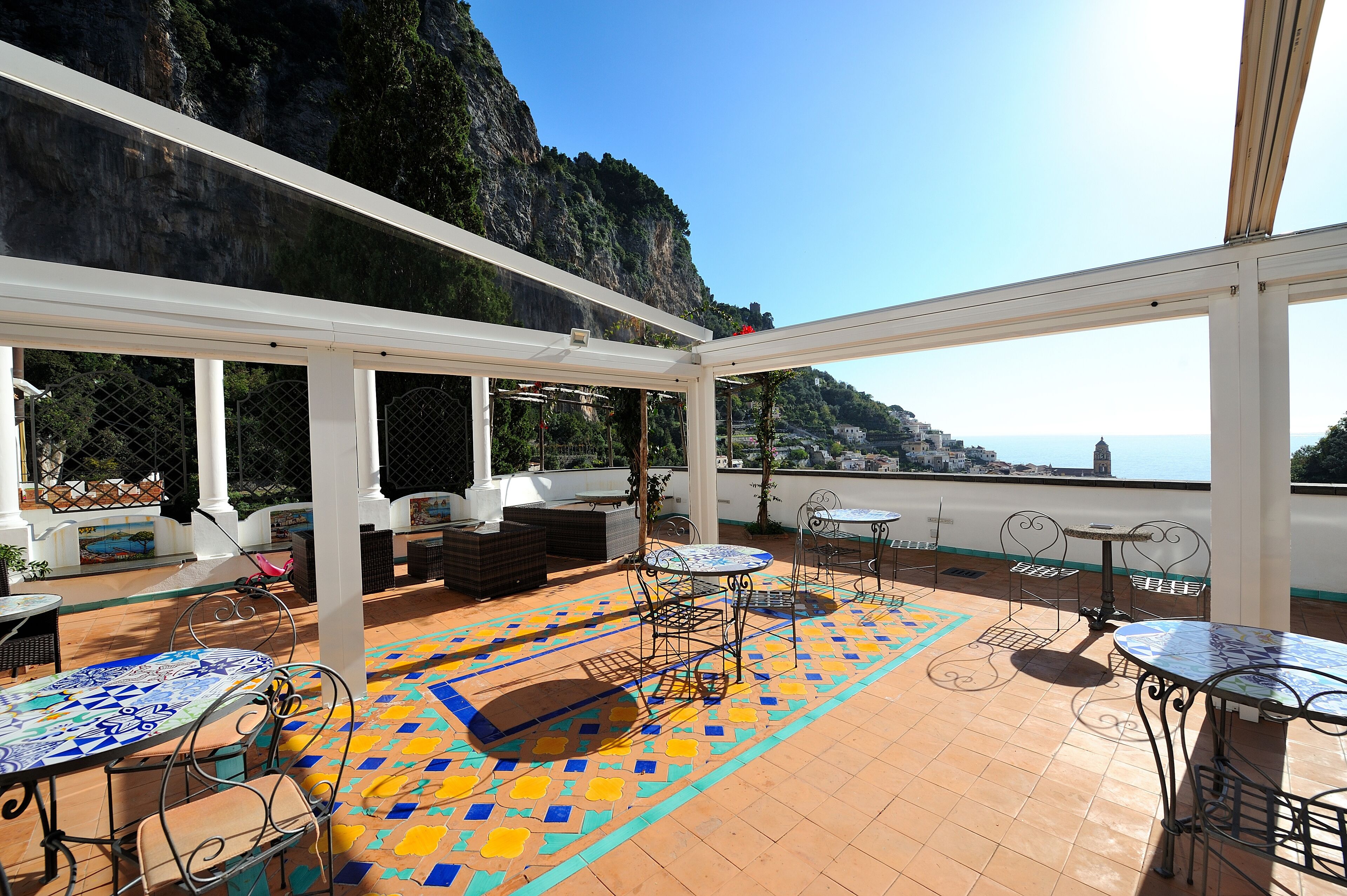 Terraço no telhado com área de estar ao ar livre, piso estampado e vista para a costa.
