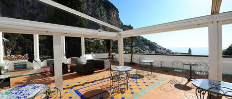 Terraço no telhado com área de estar ao ar livre, piso estampado e vista para a costa.