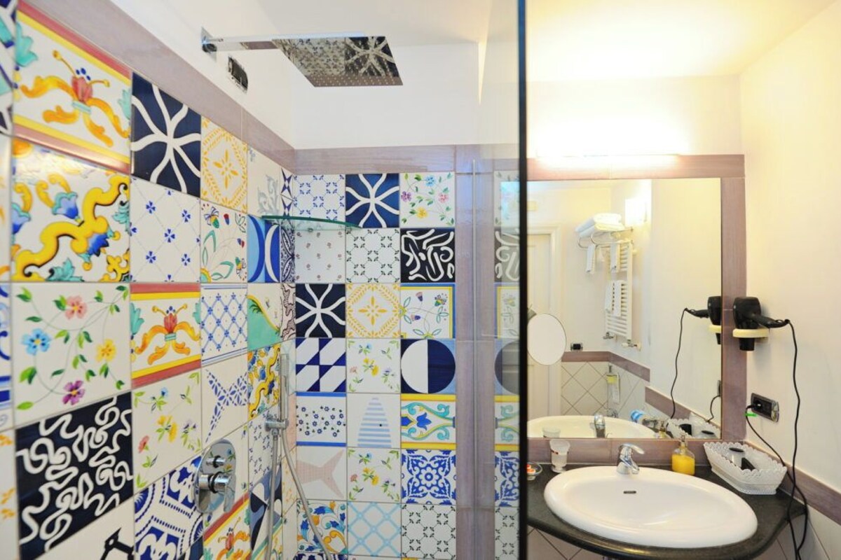 A bathroom with colorful tiles, a sink, and a mirror.