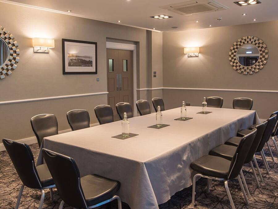 A conference room with a long table, black chairs, and decorative wall mirrors.